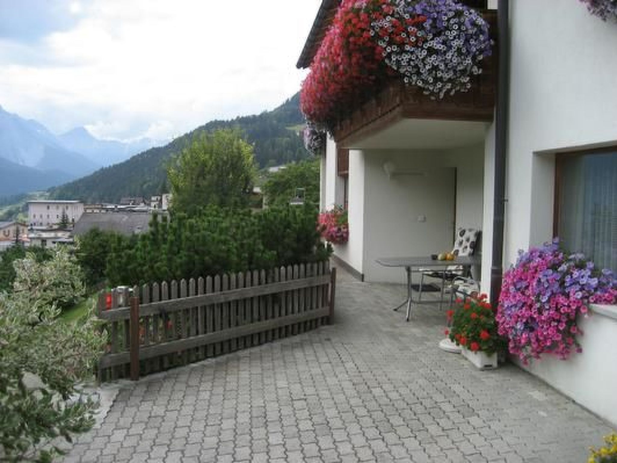 A balcony with a wooden fence, a table, and potted plants.