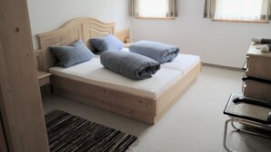 A bedroom with a wooden bed, two windows with curtains, a desk, and a chair. - Chasa Müfaits Parterre, (Tschierv) by Interhome (Tschierv)