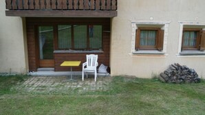 A building with a wooden balcony, a white chair, and a small table. - Chasa Müfaits Parterre, (Tschierv) by Interhome (Tschierv)
