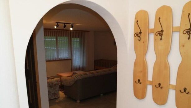 An interior with a sofa, a small table, and a wooden wall decoration. - Chasa Müfaits Parterre, (Tschierv) by Interhome (Tschierv)