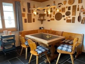 Un'accogliente zona pranzo con un tavolo e sedie in legno, una parete decorata con diverse targhe commemorative e un lampadario originale.