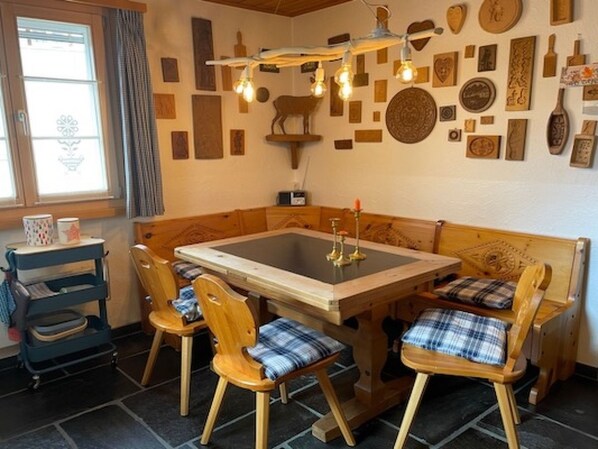 Un coin repas chaleureux avec une table et des chaises en bois, un mur orné de divers panneaux et un luminaire original.