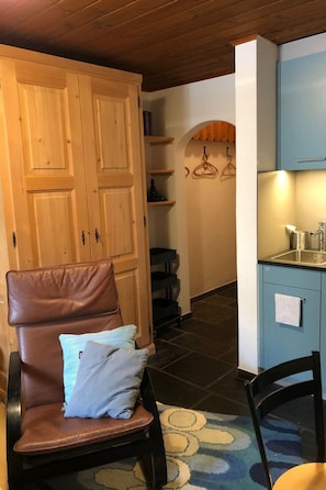 Ein gemütliches Zimmer mit einem braunen Ledersessel, einem kleinen Tisch und einem blauen Schrank.
