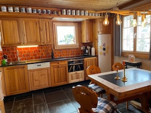 Una cucina con mobili in legno, una finestra, un tavolo da pranzo con sedie e un frigorifero.