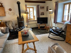 Un accogliente soggiorno con camino, televisione e comodi posti a sedere.