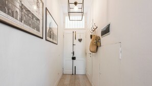 A hallway with framed pictures, a white door, a hanging bag, and a light fixture. - Golden Roof 4 by MMega (Florence)