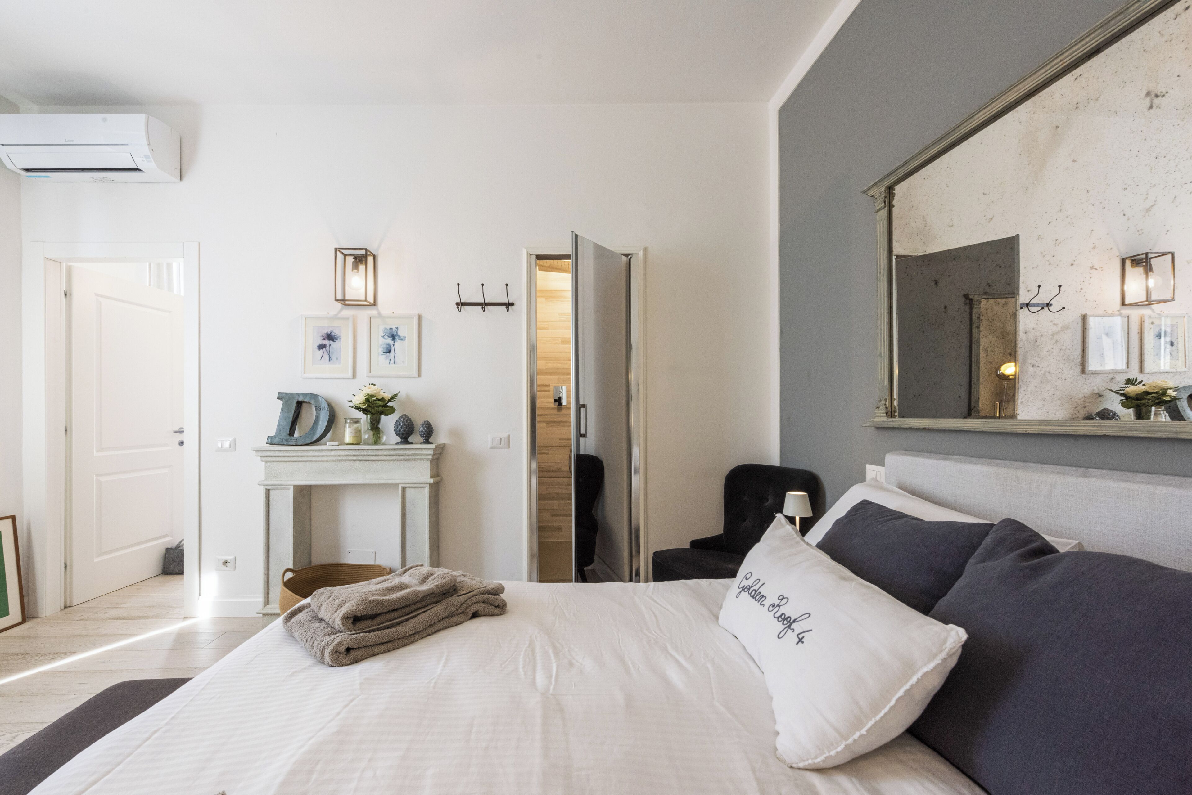 Ein Schlafzimmer mit Bett, Kommode, Spiegel und einer Tür zu einem anderen Raum.