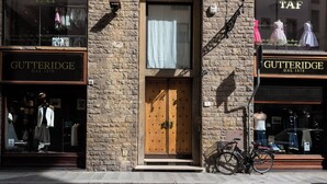 A storefront with a wooden door, a bicycle, and mannequins displaying clothing. - Golden Roof 4 by MMega (Florence)