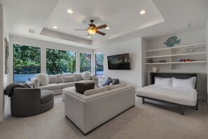 A modern living room with a sofa, a chair, a bed, and a ceiling fan. - 4BR Lake Austin Estate | Private Dock + Wake Surf Water | 200 Ft Frontage (Austin)