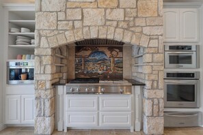 A kitchen with a stone arch, a stove, and built-in ovens. - 4BR Lake Austin Estate | Private Dock + Wake Surf Water | 200 Ft Frontage (Austin)