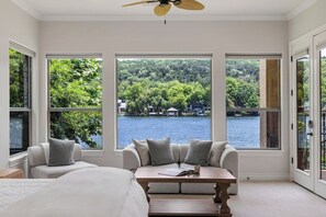 A bedroom with a large window, a bed, a seating area with a table, and a ceiling fan. - 4BR Lake Austin Estate | Private Dock + Wake Surf Water | 200 Ft Frontage (Austin)