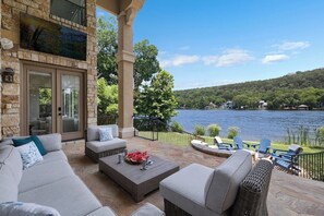 A patio with outdoor furniture, a stone wall, and a view of a lake. - 4BR Lake Austin Estate | Private Dock + Wake Surf Water | 200 Ft Frontage (Austin)