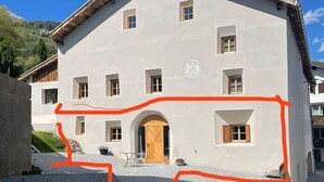 A building with a symmetrical facade, multiple windows, and a central entrance with a wooden door. - Stüvetta à Porta, (Scuol) by Interhome (Scuol)