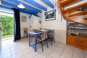 A dining area with a blue table and chairs, a wooden cabinet, and a framed picture on the wall.
