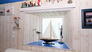 Una habitación con pared de madera, un velero modelo, una figura y una estantería con varios objetos.