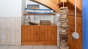 Un gabinete de madera con un pequeño estante, un juguete decorativo de cuerda y un cuadro en la pared.