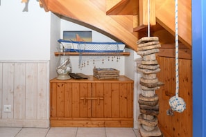 Un gabinete de madera con un pequeño estante, un juguete decorativo de cuerda y un cuadro en la pared.