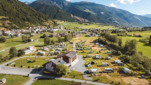 Ein ländliches Städtchen mit Kirche, einem Parkplatz mit Wohnmobilen und Bergen im Hintergrund.
