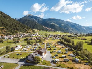 A rural town with a church, a parking lot with RVs, and mountains in the background. - Camping Muglin, (Müstair) by Interhome (Müstair)