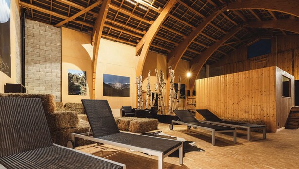 Ein rustikales Holzinnere mit Lounge-Stühlen, einer Ziegelwand und Holzbalken.