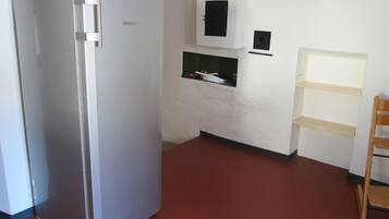 Eine Küche mit einem Edelstahl-Kühlschrank, einem Holzbstuhl und einem weißen Schrank.