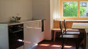 Een keuken met witte kastjes, een fornuis en een raam met uitzicht op groen.