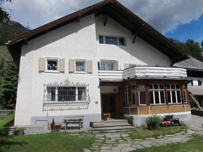 A two-story building with a stone facade, a wooden balcony, and a stone pathway leading to the entrance. - Chasa Gross, (Zernez) by Interhome (Zernez)