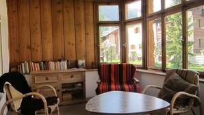 Een gezellige kamer met houten wanden, een ronde tafel en twee rieten stoelen.