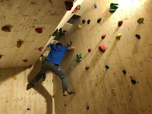 Eine Person erklimmt eine Holzwand mit bunten Griffen.