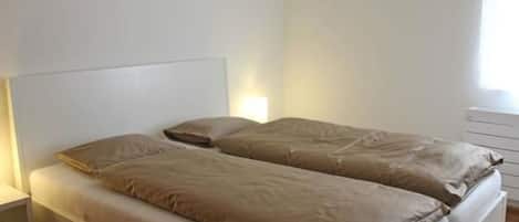 A double bed with a headboard, a bedside table, and a nightstand.