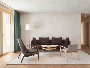 A modern living room with a sofa, two chairs, a coffee table, and a floor lamp. - Hotel Maistra 160, (Pontresina), by Interhome (Pontresina)