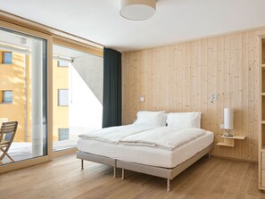 A bedroom with a bed, wooden walls, a window, and a view of a building. - Hotel Maistra 160, (Pontresina), by Interhome (Pontresina)
