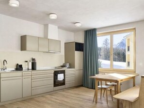 A modern kitchen with a built-in oven, a dining table with chairs, and a window with a view of a snowy landscape. - Hotel Maistra 160, (Pontresina), by Interhome (Pontresina)