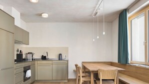 Una cocina moderna con una mesa y sillas de madera, horno empotrado y ventana con cortinas.