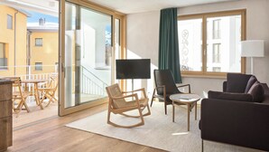 A modern living room with a sofa, chairs, a small table, a TV, and a balcony with a view of buildings. - Hotel Maistra 160, (Pontresina), by Interhome (Pontresina)