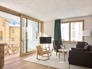 A modern living room with a sofa, chairs, a TV, and a balcony with wooden furniture. - Hotel Maistra 160, (Pontresina), by Interhome (Pontresina)