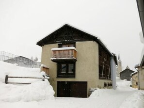 A two-story building with a balcony, surrounded by snow. - Chasa Tablà, (Guarda) by Interhome (Guarda)
