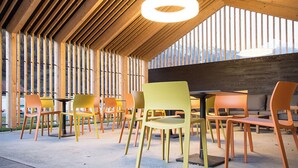 An indoor dining area with wooden slats on the ceiling, a circular light fixture, and colorful chairs. - Camping Muglin, (Müstair) by Interhome (Müstair)