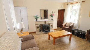 Una sala de estar con sofá, mesa de centro de madera, chimenea y televisión.