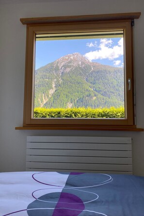 Une chambre avec une fenêtre donnant sur une montagne.