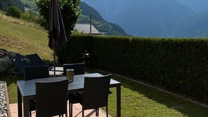 An outdoor patio with a table and chairs, a wooden deck, and a view of mountains. - Leitner, (Ramosch) by Interhome (Ramosch)