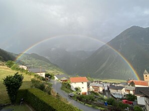 Ein ländliches Dorf mit Häusern, einer kurvenreichen Straße und Bergen im Hintergrund.
