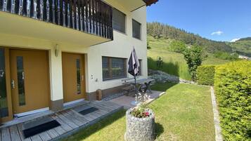 Uma casa moderna de dois andares com varanda, deck de madeira e jardim bem cuidado.