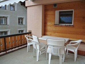 A balcony with a table and chairs, a wooden wall, and a window with a view. - Mugliner 117A, (Ftan) by Interhome (Ftan)