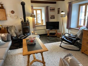 A cozy living room with a fireplace, a television, and comfortable seating. - Mugliner 117A, (Ftan) by Interhome (Ftan)