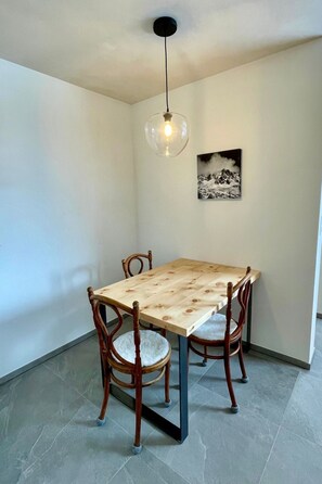 Een eetruimte met een houten tafel en stoelen, een hanglamp en een ingelijste foto aan de muur.