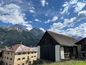 Ein rustikales Gebäude mit geneigtem Dach, neben einem mehrstöckigen Gebäude mit sichtbaren Fenstern und einem Balkon.