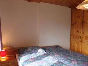 Un dormitorio con cama, mesita de noche, lámpara y paredes de madera.