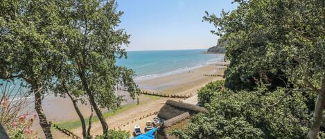 A beach view with a thatched-roof building and a staircase leading down to the beach.