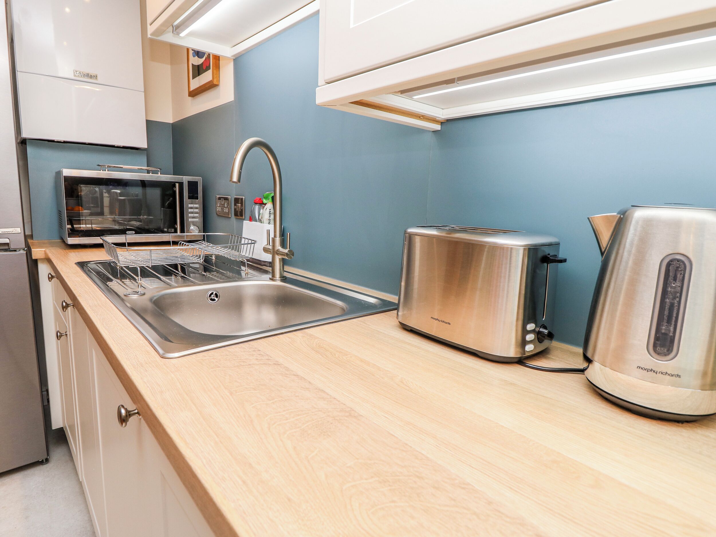 A modern kitchen with a stainless steel sink, a toaster, and a kettle.